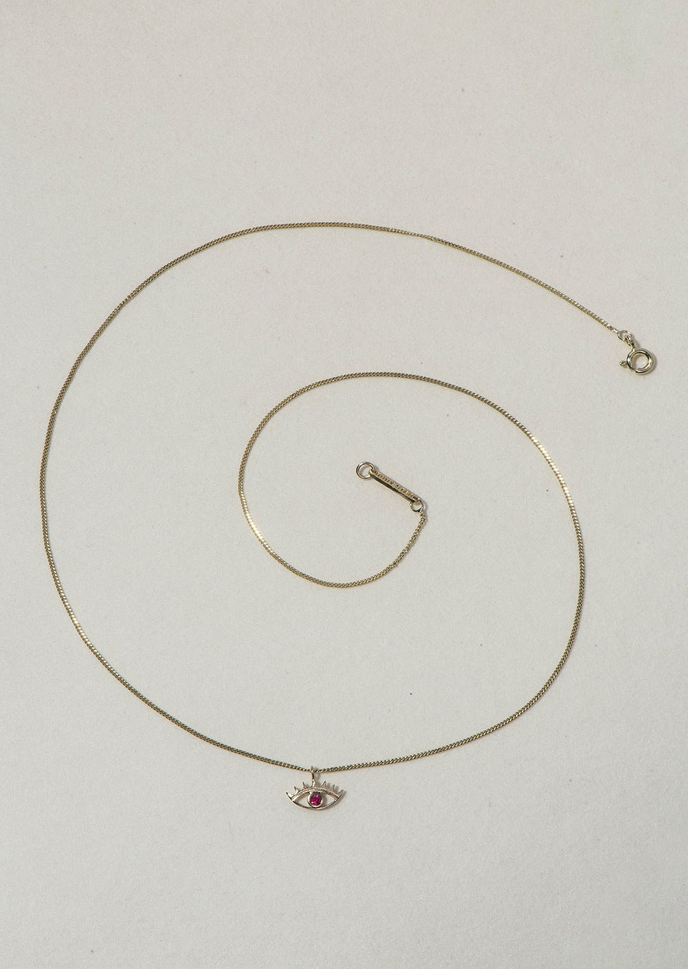 MINI EYE NECKLACE
English

A miniature eye necklace handcrafted in 14K solid gold and suspended from a delicate curb chain. Small in scale yet rich in meaning, it is a quiet symbolic object that balances sculptural simplicity with a sense of protection and inner awareness.

The symbolism of the eye has existed for thousands of years and has always been associated with consciousness and perception. The Evil Eye is worn for protection, the All-Seeing Eye represents divine providence, and the Third Eye symboli