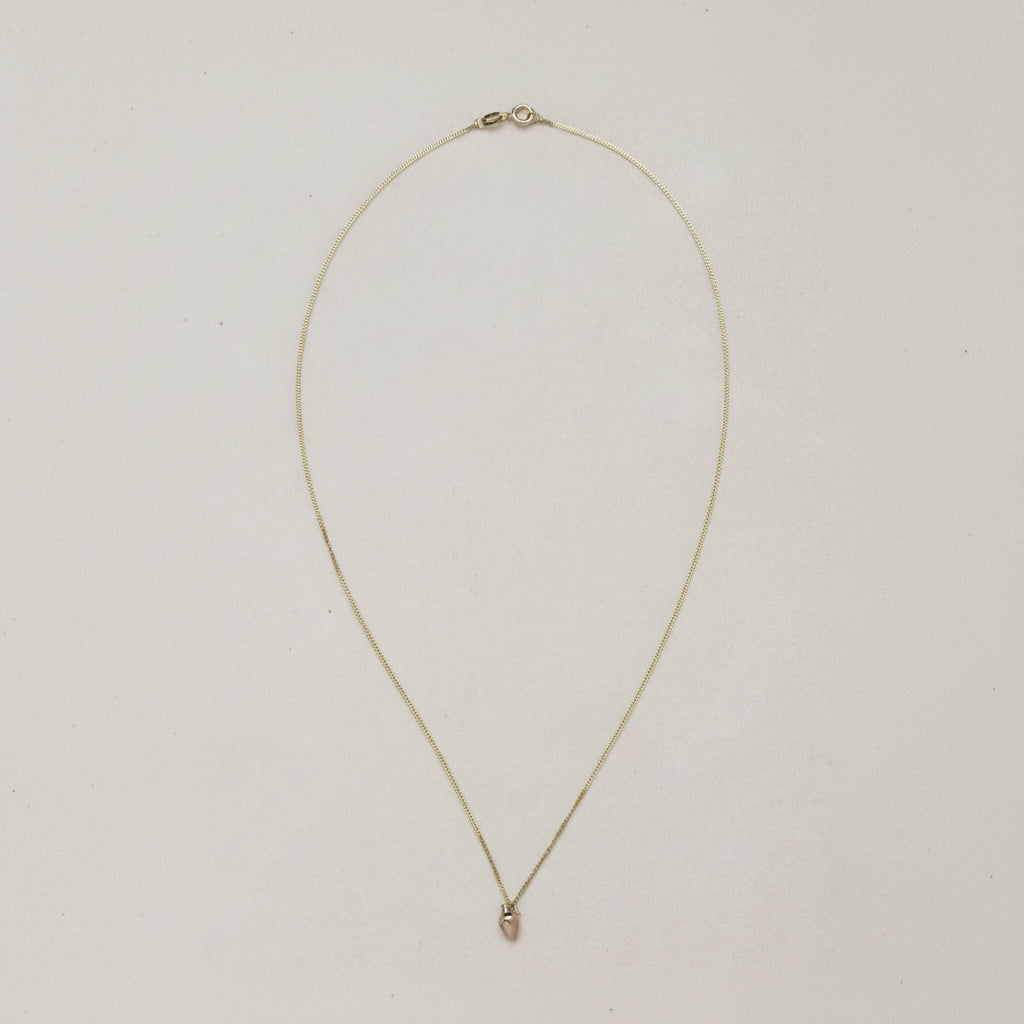 MINI VASE NECKLACE

A miniature vessel necklace handcrafted in 14K solid gold and suspended from a delicate curb chain. Small in scale yet rich in symbolism, it is a sculptural object that balances softness, femininity, and quiet presence.

Throughout history, the vessel has been a feminine, mystical, and ceremonial symbol. In biblical tradition, a vessel represents a person chosen to carry purpose and meaning. At its essence, the vessel symbolizes the human body—particularly the female body that ho