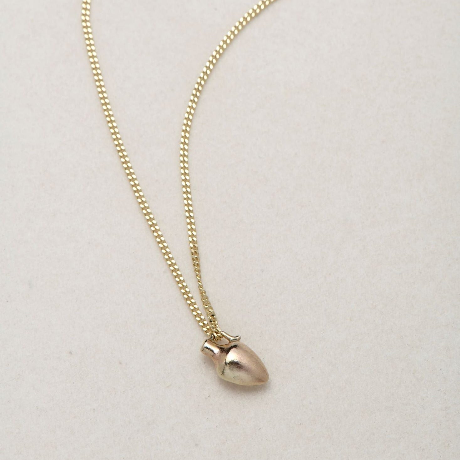 MINI VASE NECKLACE
English

A miniature vessel necklace handcrafted in 14K solid gold and suspended from a delicate curb chain. Small in scale yet rich in symbolism, it is a sculptural object that balances softness, femininity, and quiet presence.

Throughout history, the vessel has been a feminine, mystical, and ceremonial symbol. In biblical tradition, a vessel represents a person chosen to carry purpose and meaning. At its essence, the vessel symbolizes the human body—particularly the female body that ho