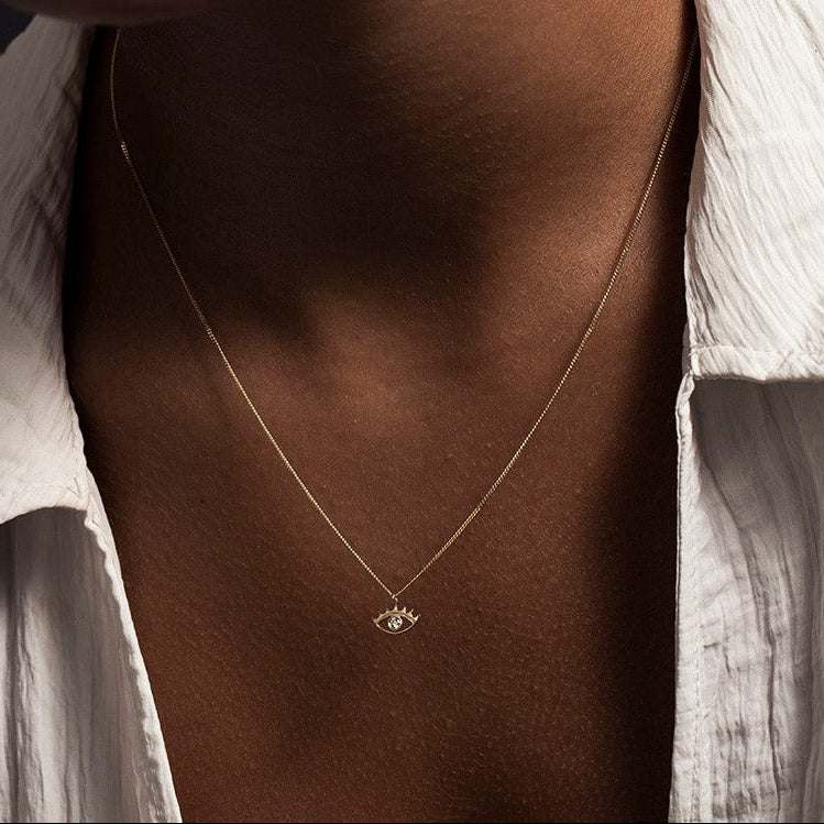 MINI EYE NECKLACE
English

A miniature eye necklace handcrafted in 14K solid gold and suspended from a delicate curb chain. Small in scale yet rich in meaning, it is a quiet symbolic object that balances sculptural simplicity with a sense of protection and inner awareness.

The symbolism of the eye has existed for thousands of years and has always been associated with consciousness and perception. The Evil Eye is worn for protection, the All-Seeing Eye represents divine providence, and the Third Eye symboli