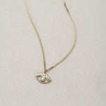 MINI EYE NECKLACE
English

A miniature eye necklace handcrafted in 14K solid gold and suspended from a delicate curb chain. Small in scale yet rich in meaning, it is a quiet symbolic object that balances sculptural simplicity with a sense of protection and inner awareness.

The symbolism of the eye has existed for thousands of years and has always been associated with consciousness and perception. The Evil Eye is worn for protection, the All-Seeing Eye represents divine providence, and the Third Eye symboli
