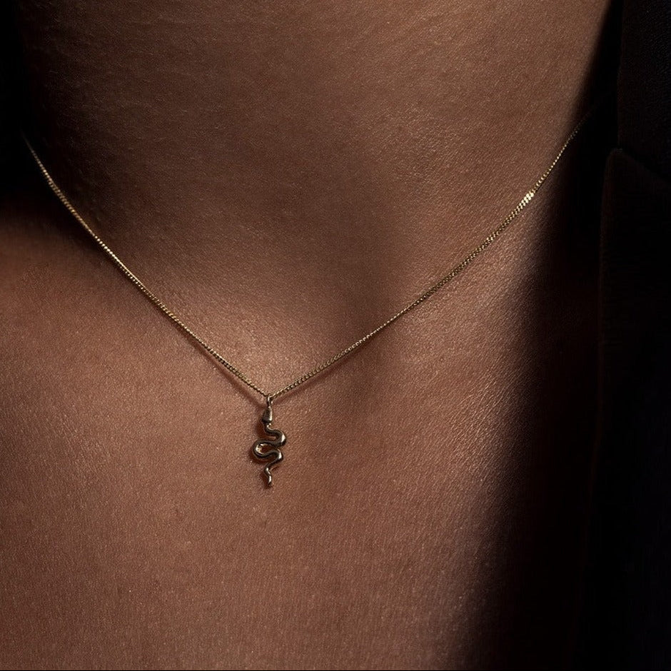 A miniature snake necklace handcrafted in 14K solid gold, suspended from a delicate curb chain. Small in scale yet rich in symbolism, it balances sculptural simplicity with quiet presence.

Throughout history, snakes have symbolized fertility, creative life force, and renewal. As snakes shed their skin to survive, they remind us of the importance of releasing what no longer serves us in order to grow and transform. They are enduring symbols of rebirth, healing, and personal evolution.

The MINI SNAKE NECKLA