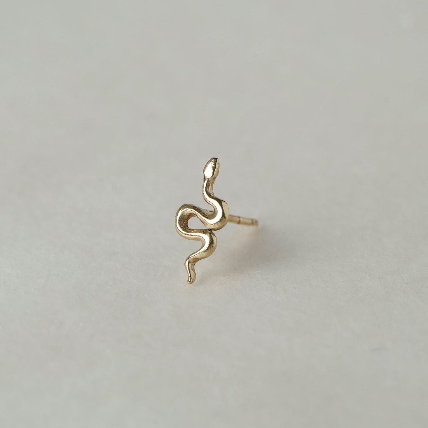 MINI SNAKE STUD

A miniature snake crafted in 14K solid gold. A small symbolic object with a quiet presence, balancing sculptural simplicity with profound meaning.

Historically, snakes have represented fertility, creative life force, and renewal. As snakes shed their skin in order to survive, they remind us of the importance of releasing what no longer serves us so that we may grow and transform.

The MINI SNAKE STUD is a handcrafted Fine Jewelry piece, created in the Ruby Star studio by local artisans. It