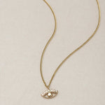 MINI EYE NECKLACE
English

A miniature eye necklace handcrafted in 14K solid gold and suspended from a delicate curb chain. Small in scale yet rich in meaning, it is a quiet symbolic object that balances sculptural simplicity with a sense of protection and inner awareness.

The symbolism of the eye has existed for thousands of years and has always been associated with consciousness and perception. The Evil Eye is worn for protection, the All-Seeing Eye represents divine providence, and the Third Eye symboli